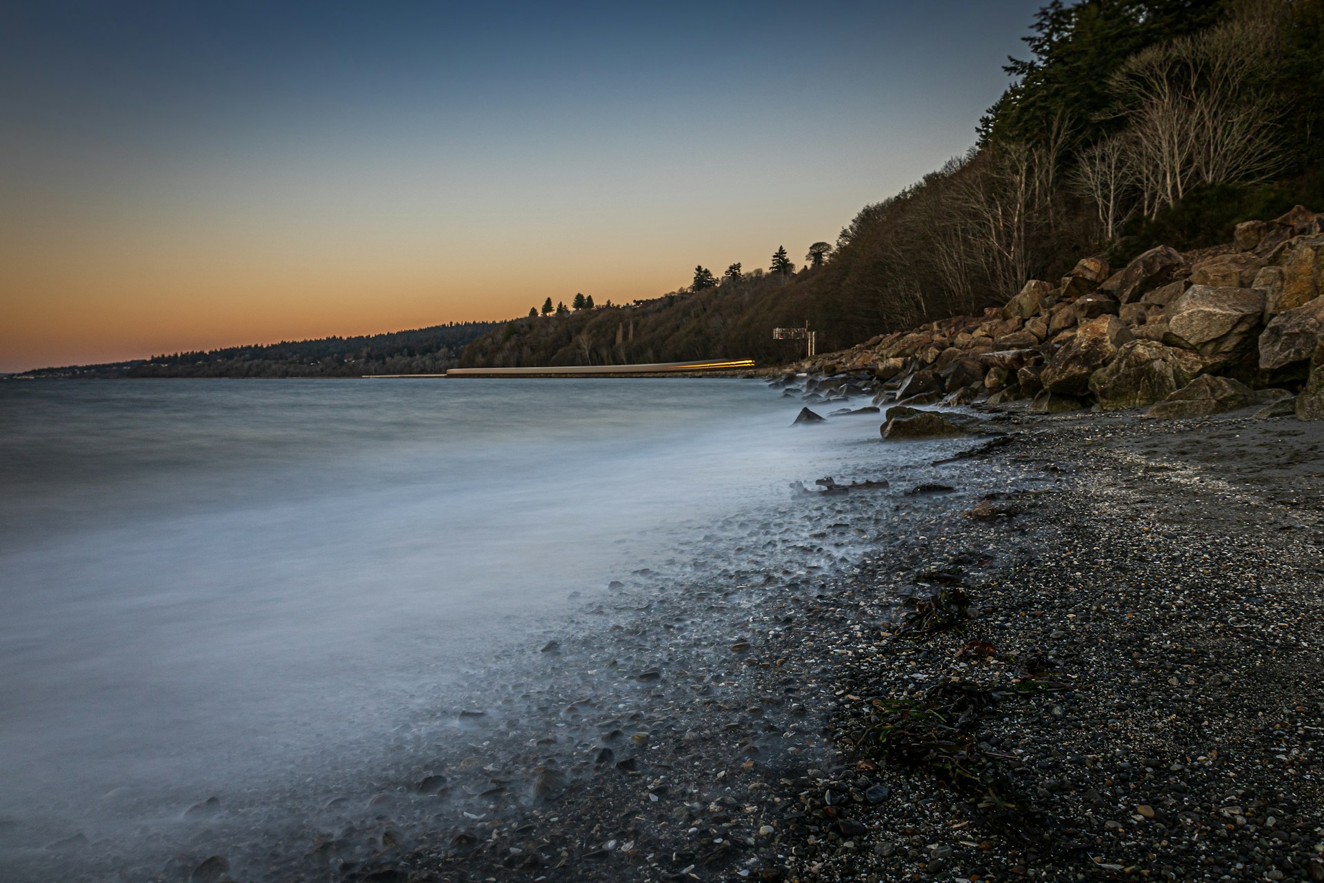 A serene aerial shot of a misty coastline at dawn, captured by a DJI drone, highlighting the delicate interplay of light and shadow.