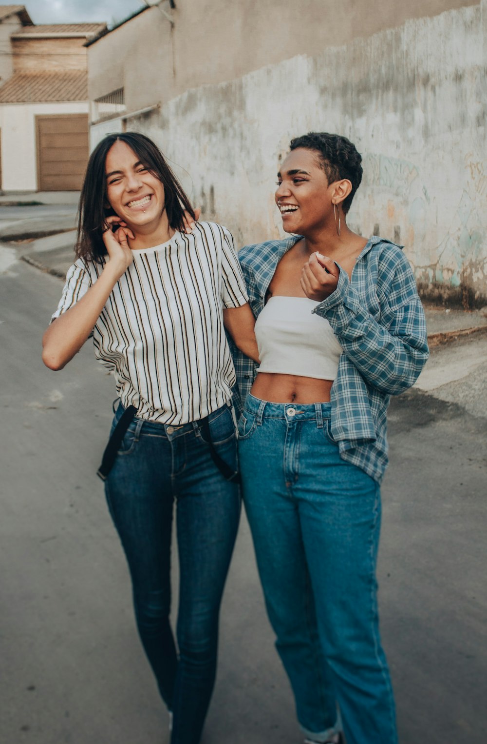 woman in white and black striped shirt and blue denim jeans standing beside woman in blue