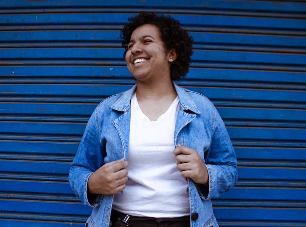 woman in blue denim jacket standing beside blue wall