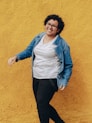woman in blue denim jacket and black pants standing and smiling