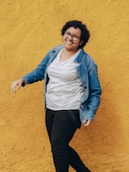 woman in blue denim jacket and black pants standing and smiling