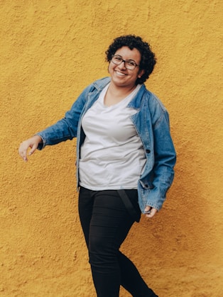 woman in blue denim jacket and black pants standing and smiling