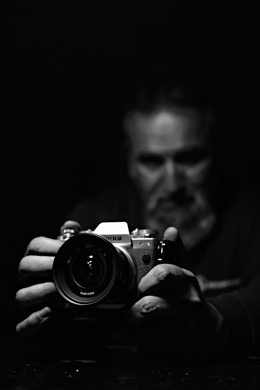 Foto en escala de grises de un hombre sosteniendo una cámara