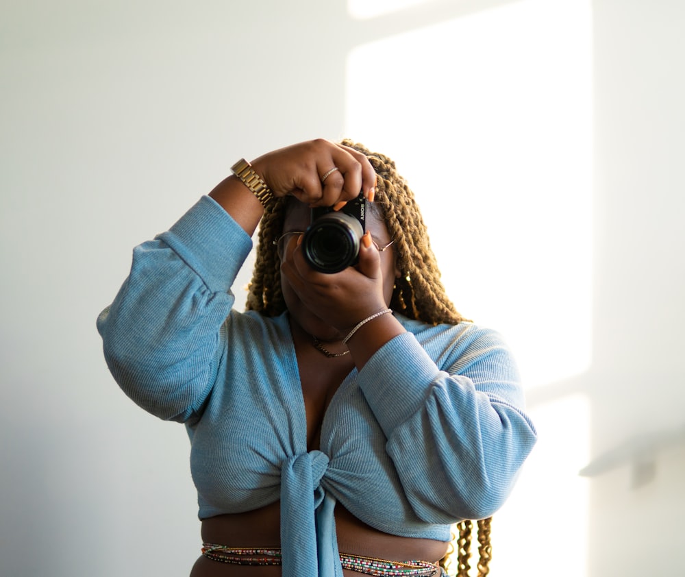 woman in blue long sleeve shirt holding black dslr camera