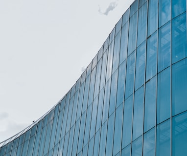 blue glass walled building under white clouds during daytime
