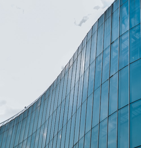 blue glass walled building under white clouds during daytime