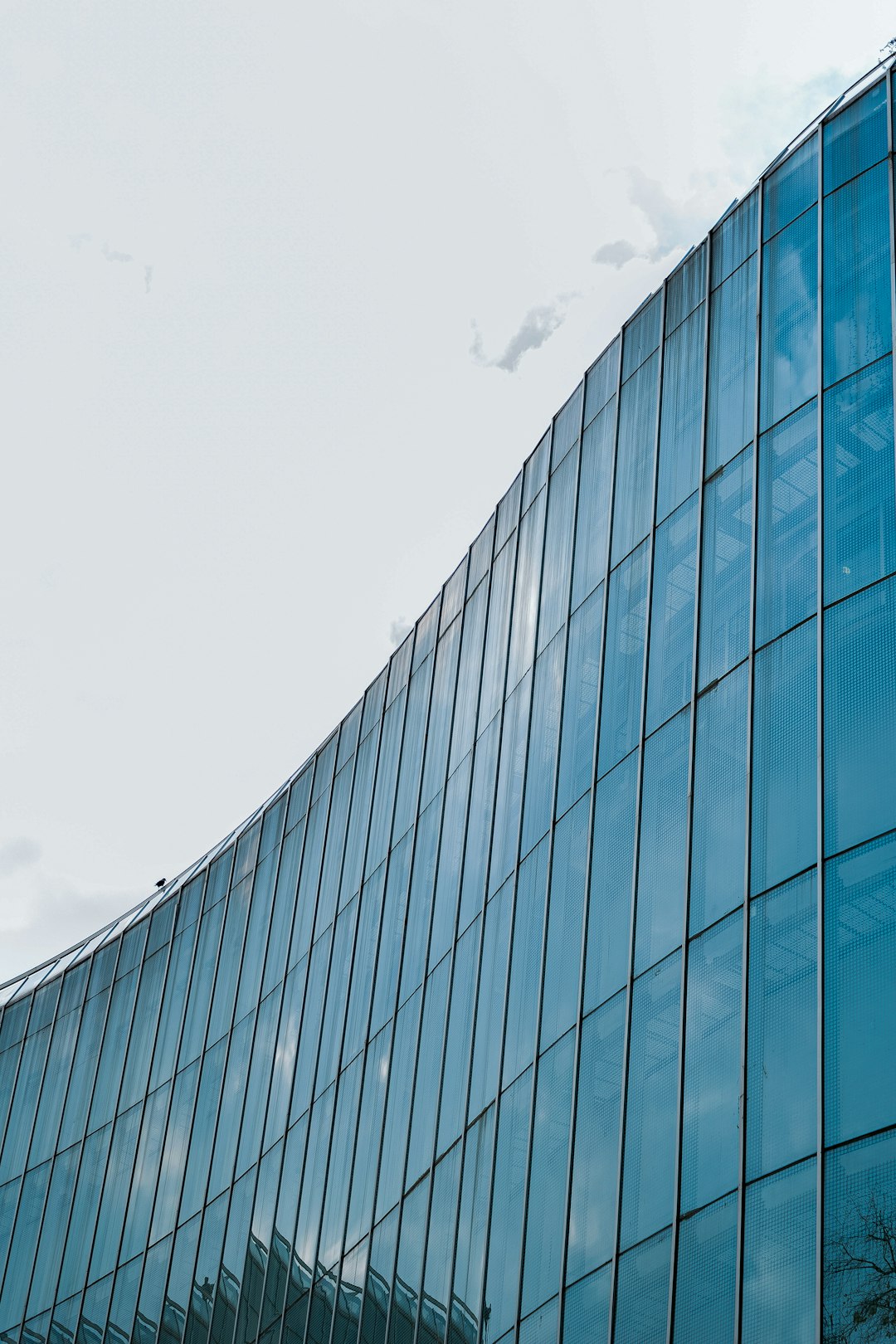 blue glass walled building under white clouds during daytime