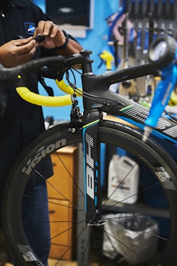 man in black jacket holding black bicycle wheel
