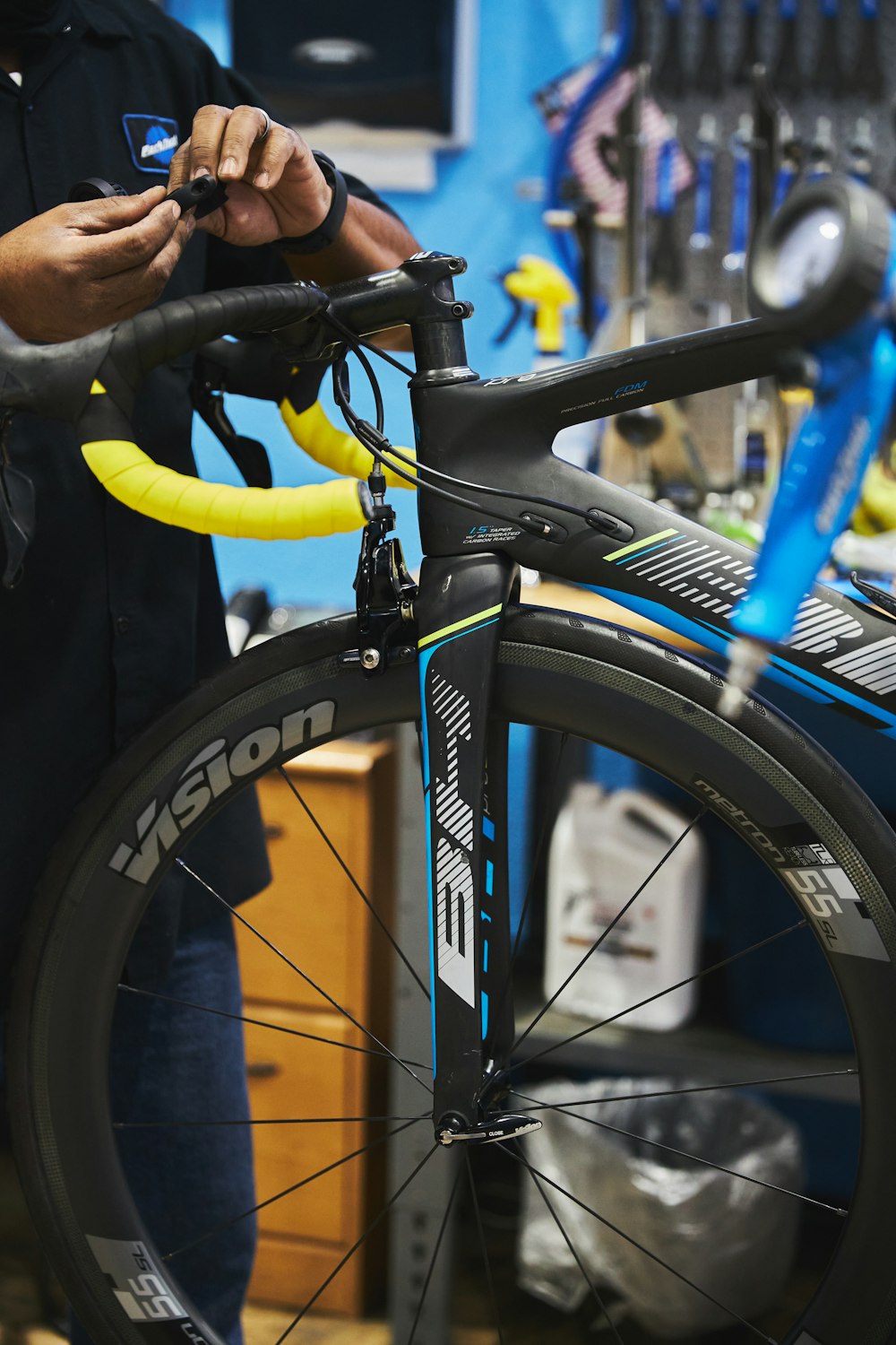 homme en veste noire tenant une roue de vélo noire