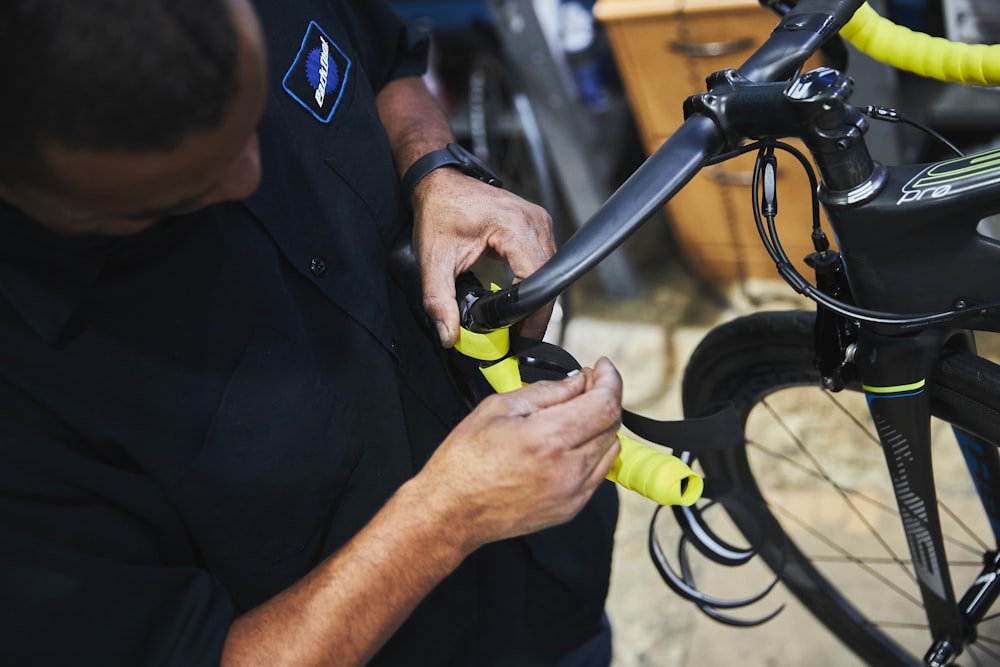 man in black polo shirt holding black bicycle handle bar