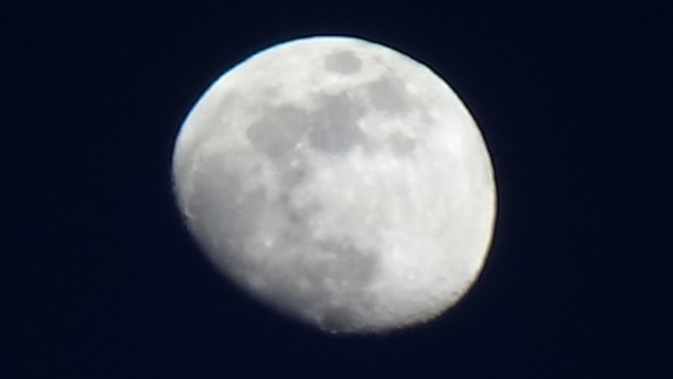 A close-up view of the moon with visible craters and surface details set against a dark sky.