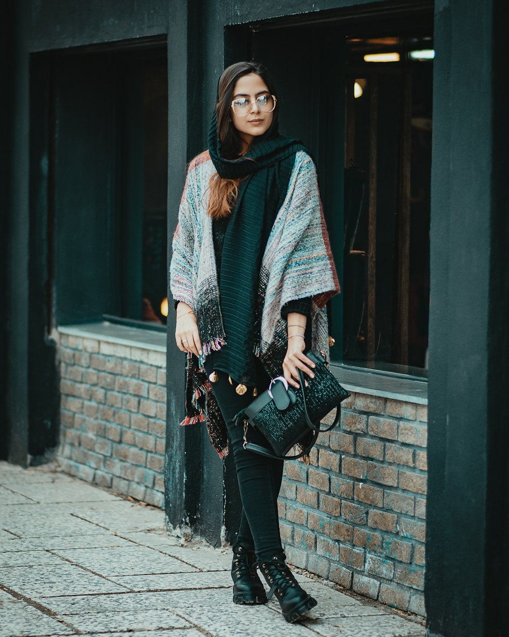 woman in black and white long sleeve shirt and black pants standing on sidewalk during daytime