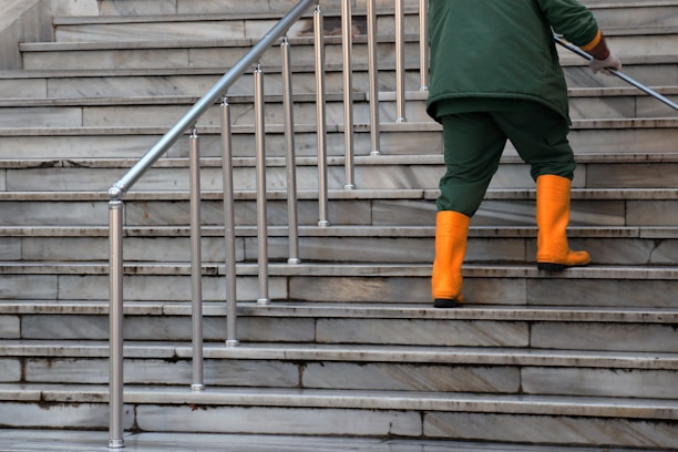 person in green jacket and brown pants walking on gray concrete stairs