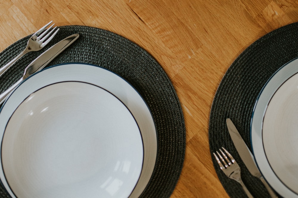 assiette ronde blanche à côté d’une fourchette et d’un couteau en argent