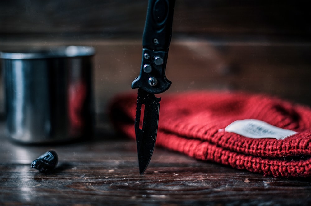 schwarz-silbernes Messer auf braunem Holztisch