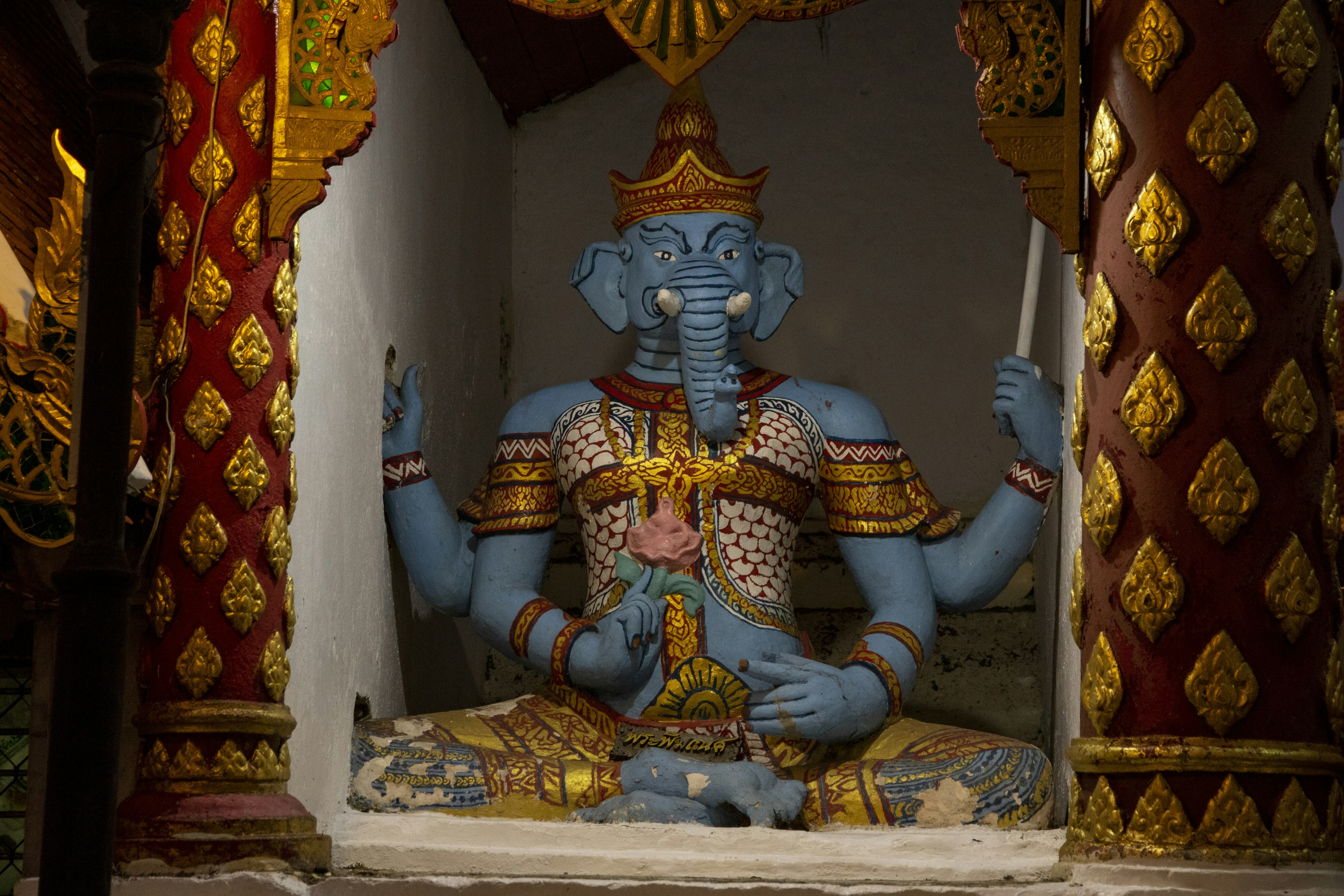 estatua dorada de la deidad hindú en tela floral blanca y amarilla