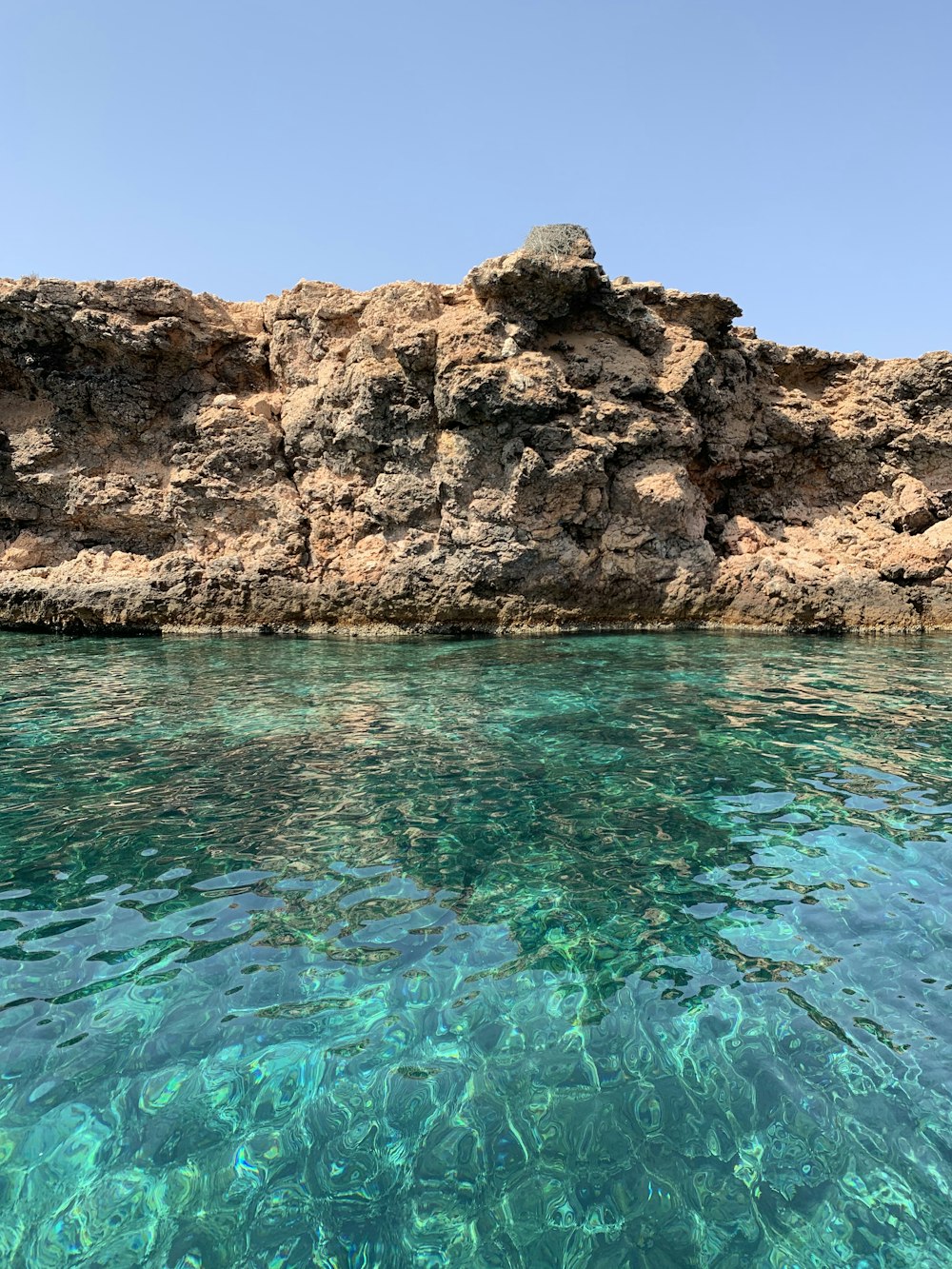 brown rock formation beside blue body of water during daytime