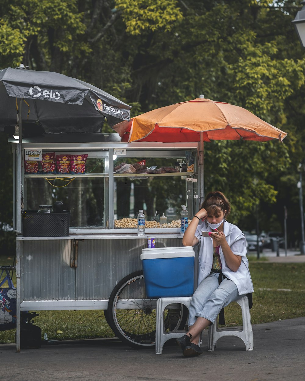 woman in white long sleeve shirt sitting on chair under red umbrella during daytime