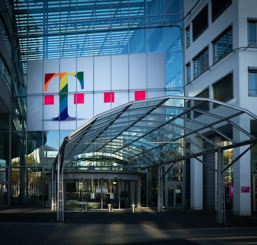 white red and yellow flags on pole in front of glass building