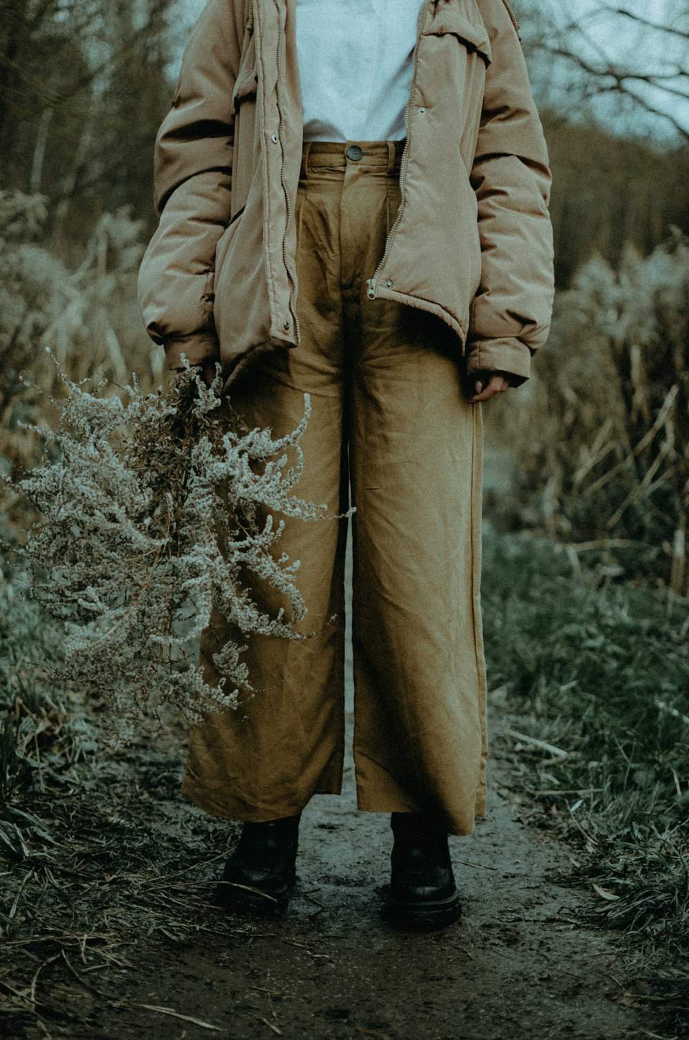 person in brown coat standing on grass field
