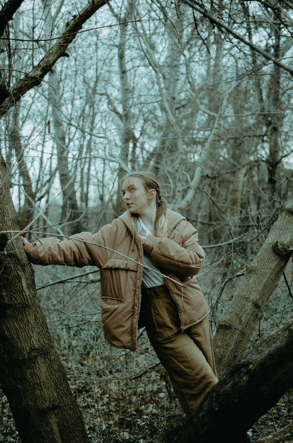 woman in brown coat standing beside brown tree