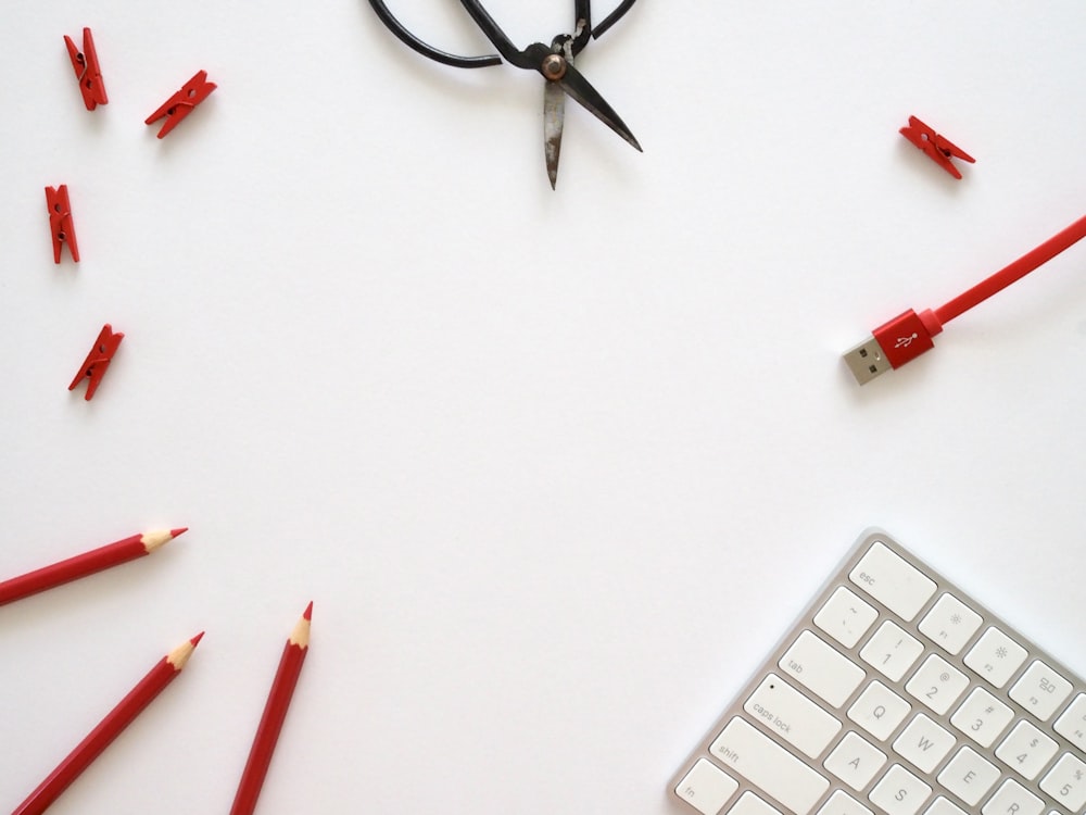 white and red pen beside white computer keyboard