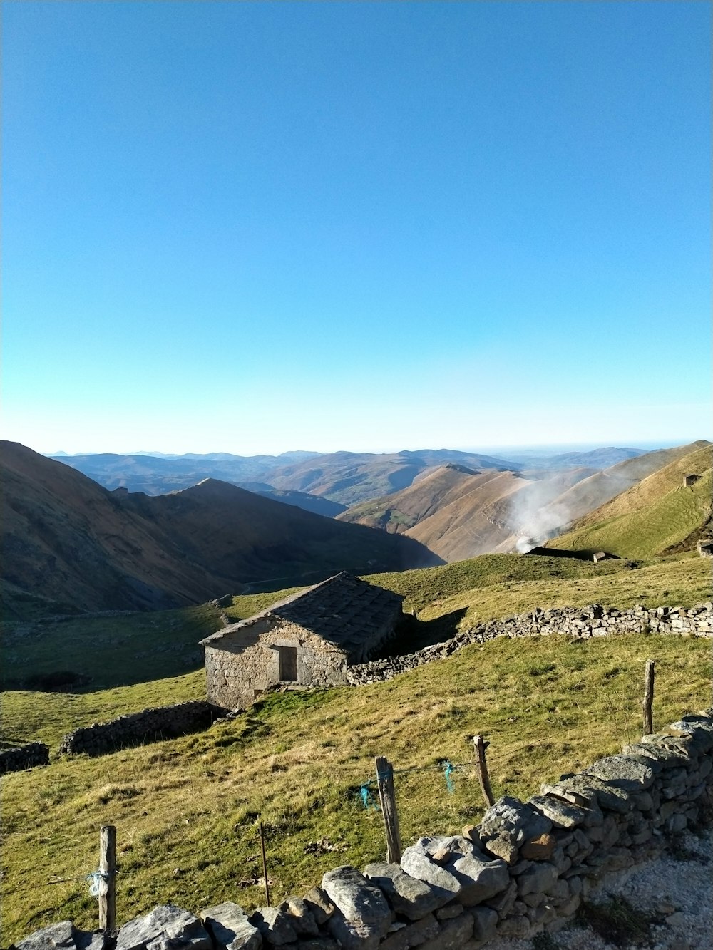 green grass field near mountain under blue sky during daytime