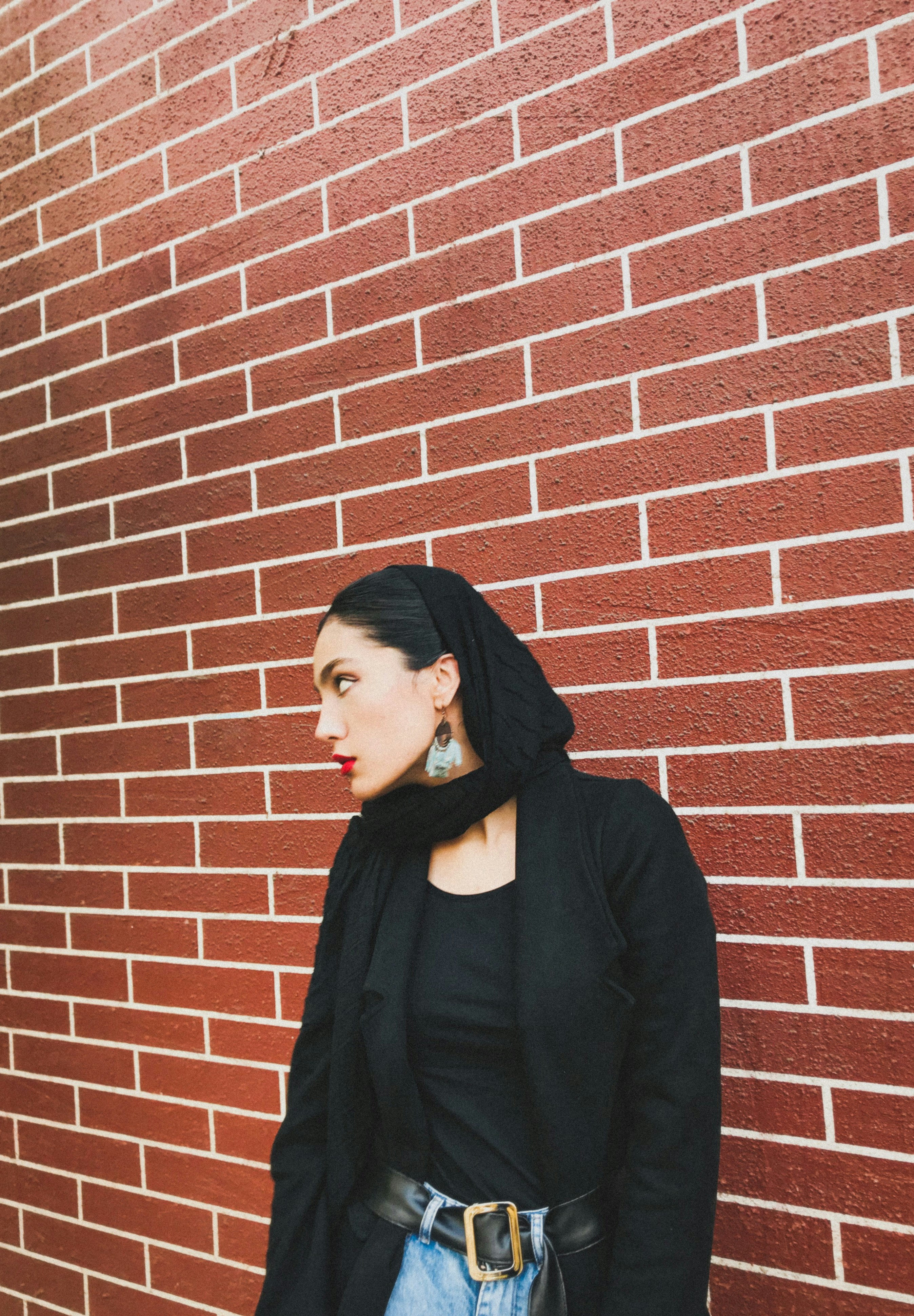 woman in black turtleneck long sleeve shirt standing beside brown brick wall