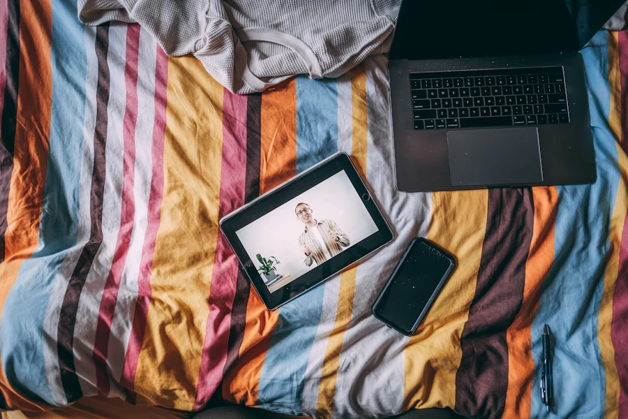 Laptop and smartphone arranged together on a bed for connected use