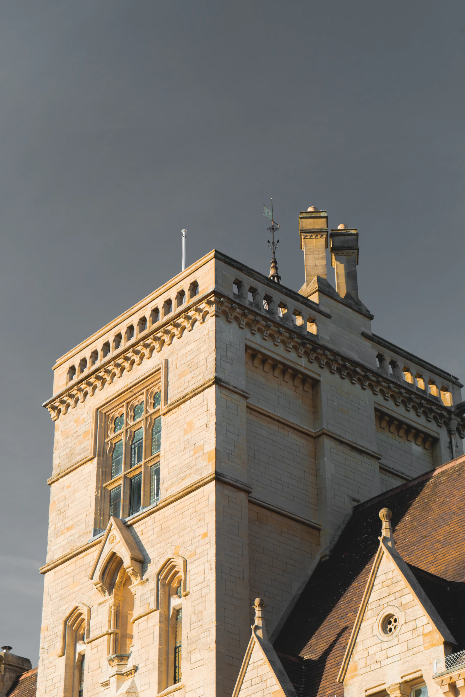 A historic stone college building under a clear blue sky in England