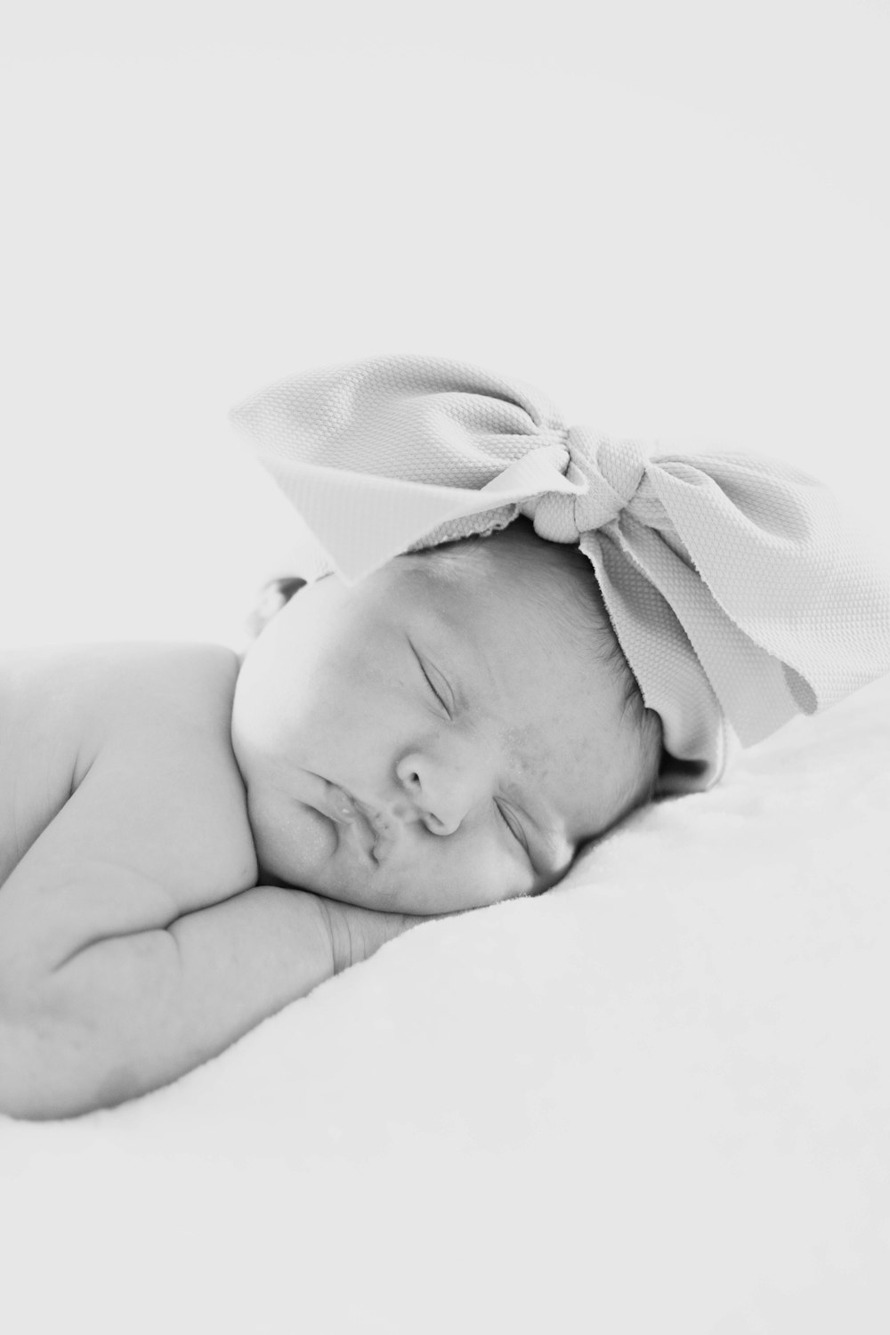 baby in white hat lying on white textile