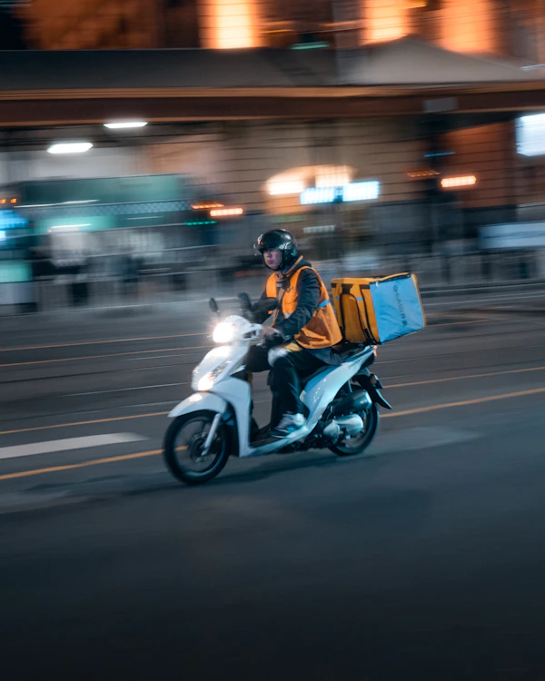 A delivery rider on a scooter at night