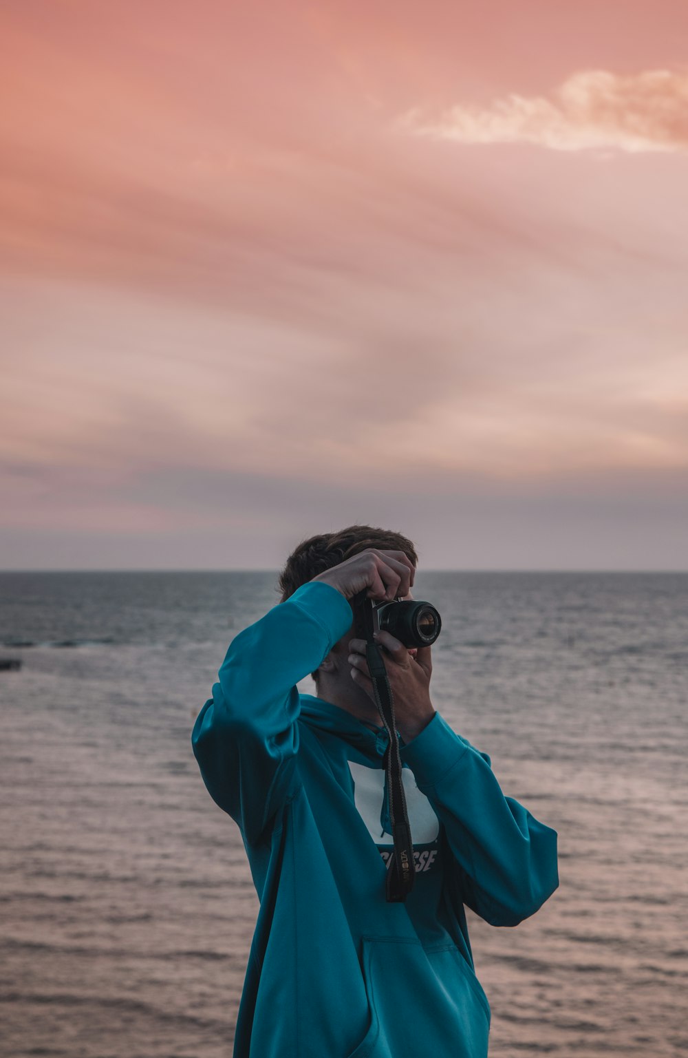 person in blue hoodie using black dslr camera