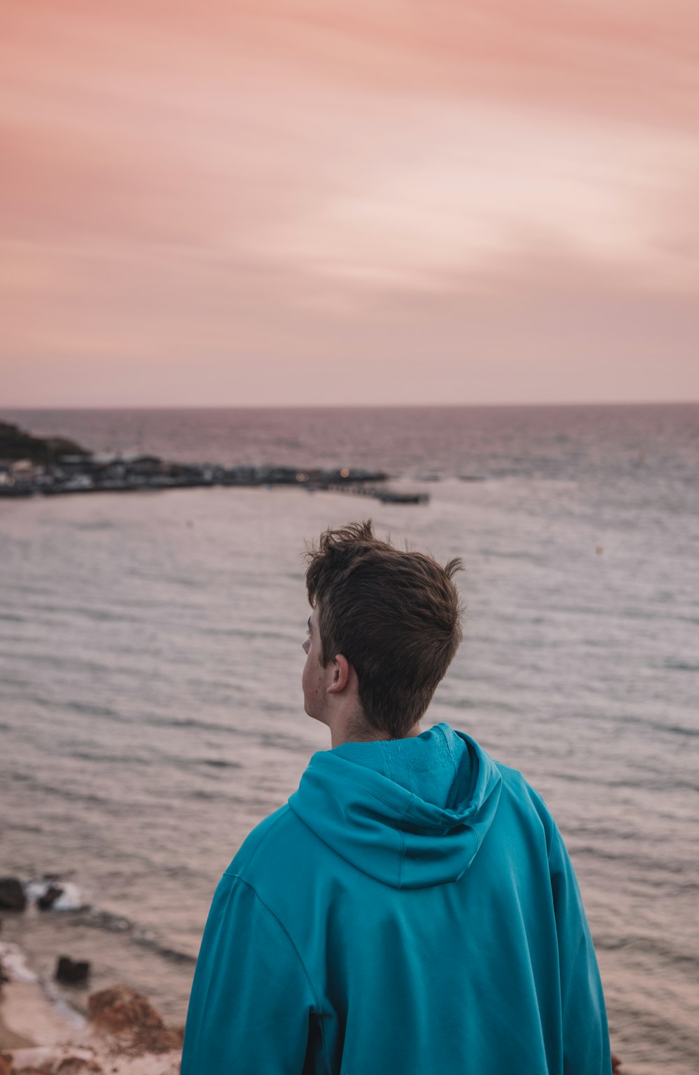 man in blue hoodie standing near body of water during daytime