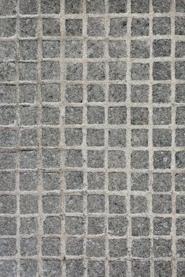 A texture consisting of evenly spaced stone tiles arranged in a grid pattern. Each tile has a rough, textured surface with slight variations in color and tone.
