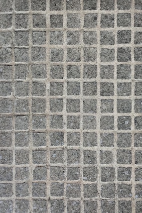 A texture consisting of evenly spaced stone tiles arranged in a grid pattern. Each tile has a rough, textured surface with slight variations in color and tone.