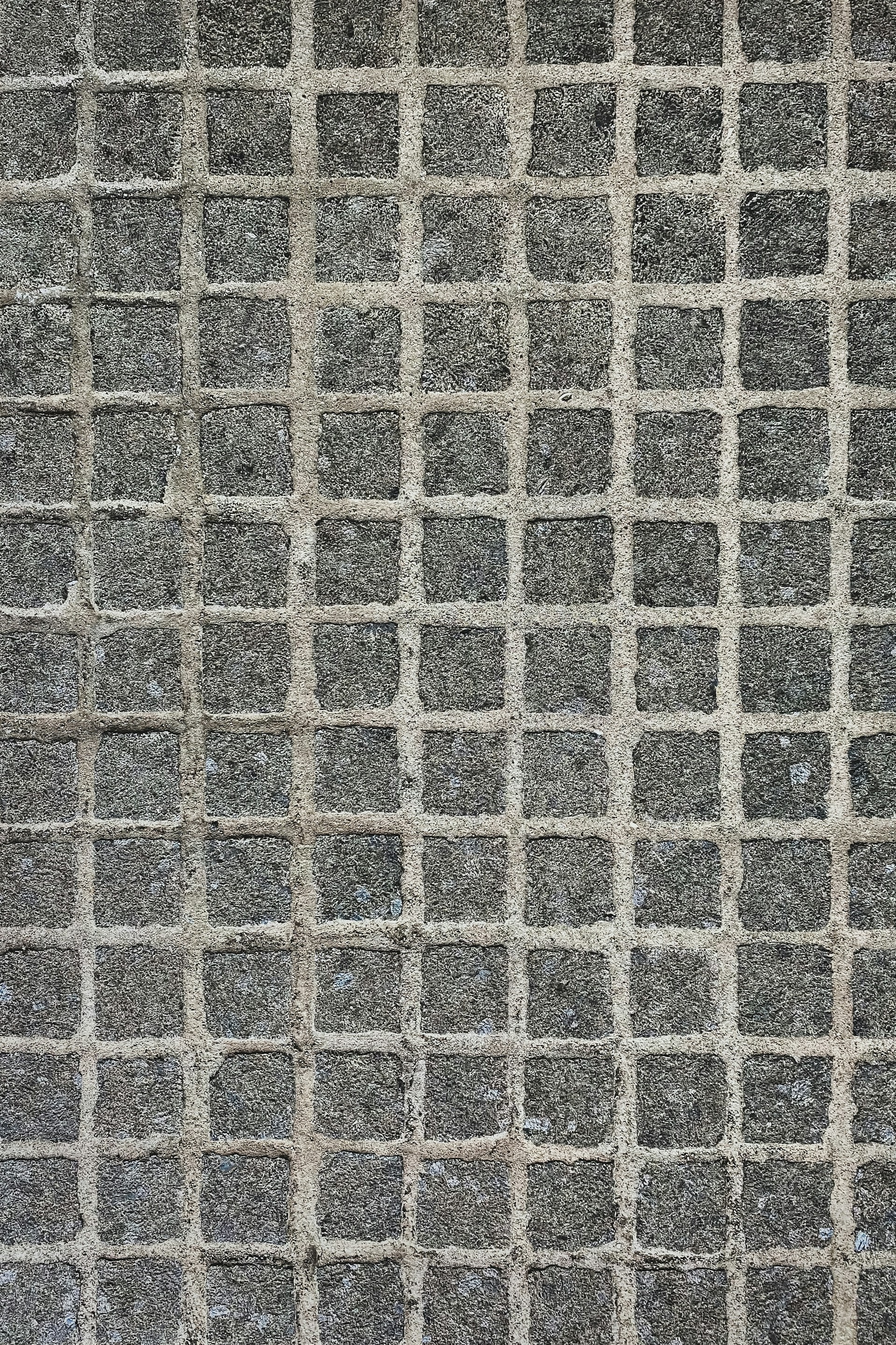A texture consisting of evenly spaced stone tiles arranged in a grid pattern. Each tile has a rough, textured surface with slight variations in color and tone.