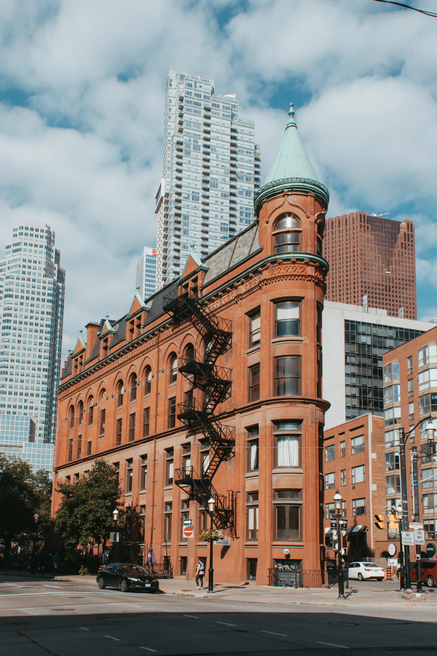 The historic red brick Gooderham Flatiron Building in downtown Toronto framed by glass office towers and a cloudy Ontario sky