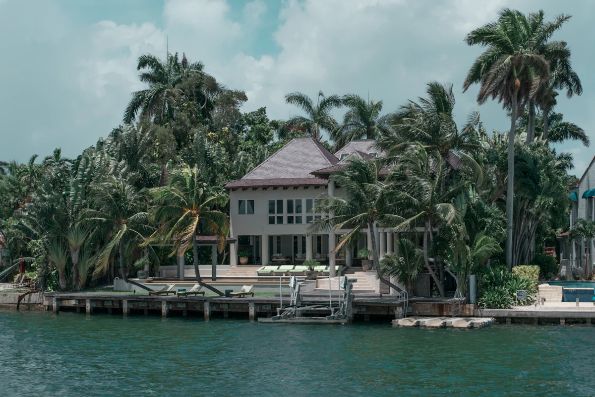 Waterfront house surrounded by palm trees with a dock on the water