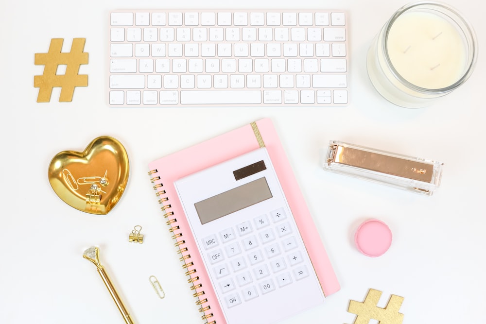 pink and white calculator beside silver and gold key