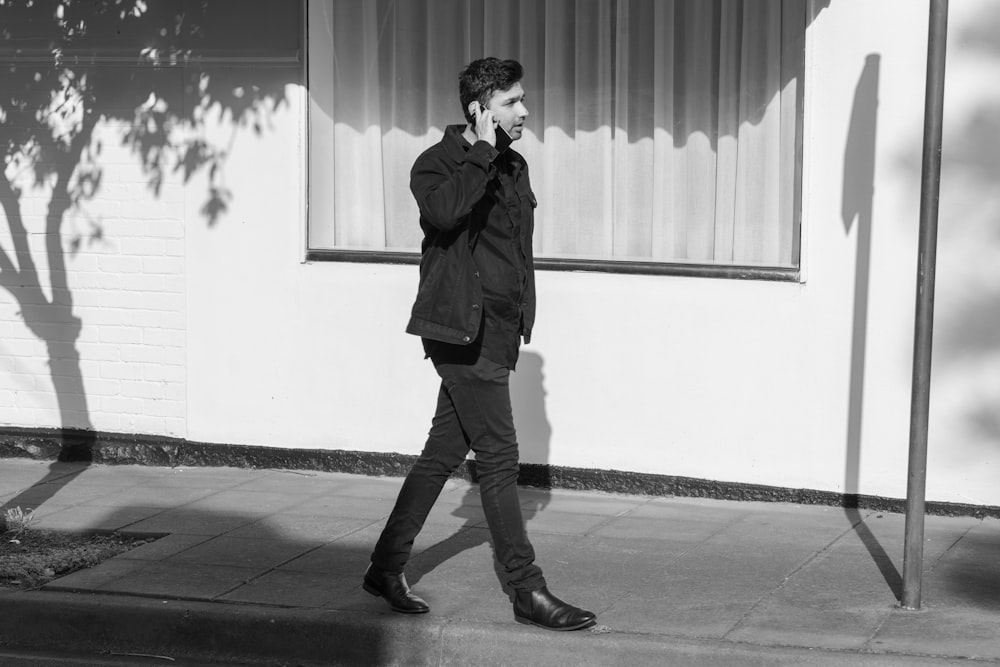 man in black jacket and black pants standing near window