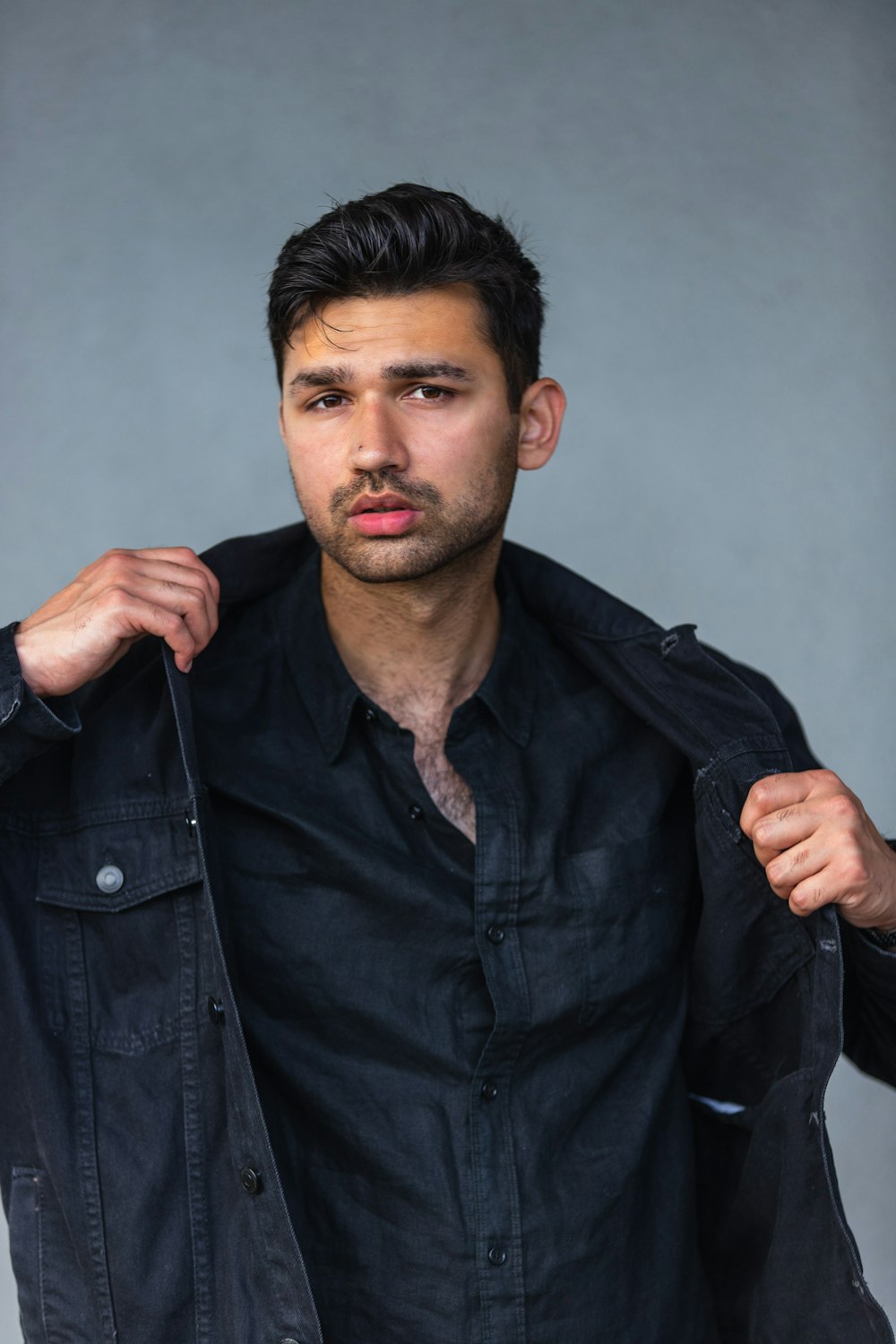 a man in a black shirt is holding a jacket