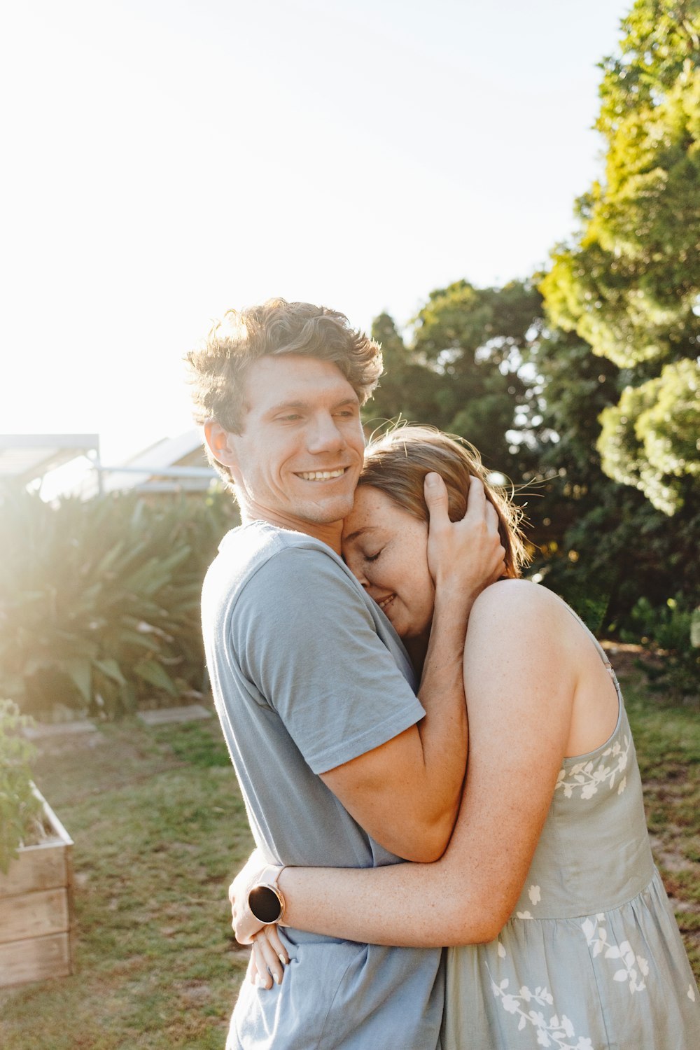 man in gray crew neck t-shirt hugging woman in white tank top