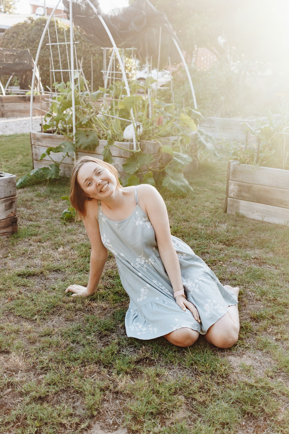 昼間、緑の芝生の上に座る白いノースリーブの女性