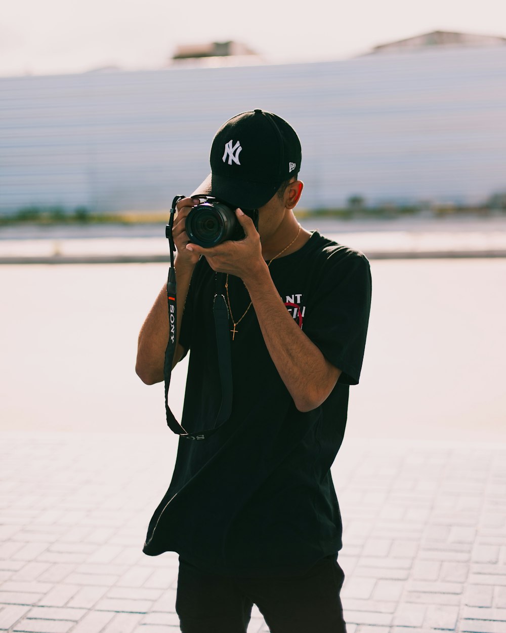 uomo in t-shirt nera che tiene la fotocamera reflex nera