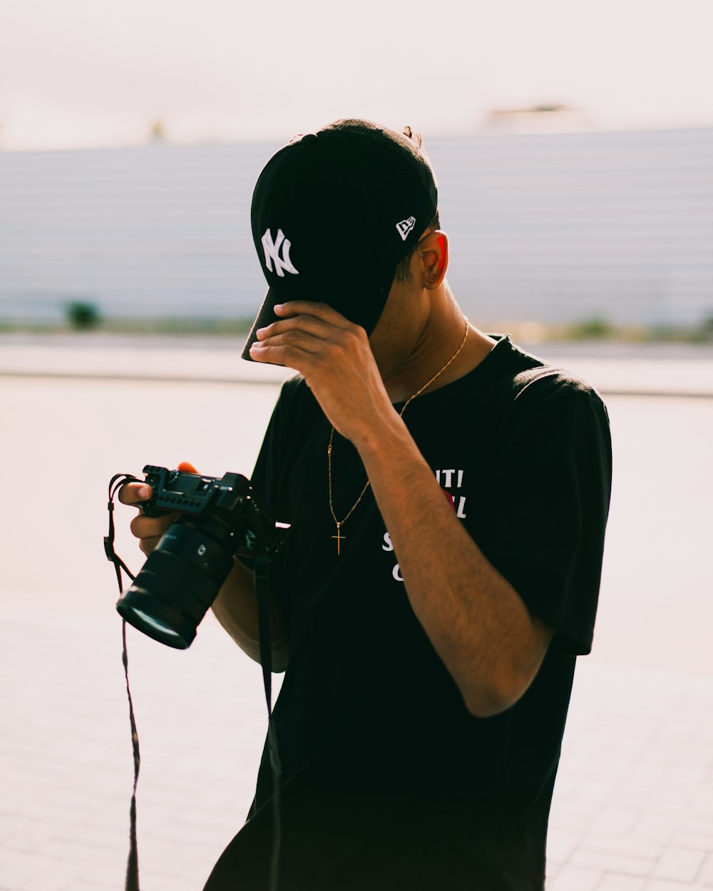 Hombre con camiseta negra de cuello redondo sosteniendo una cámara DSLR negra