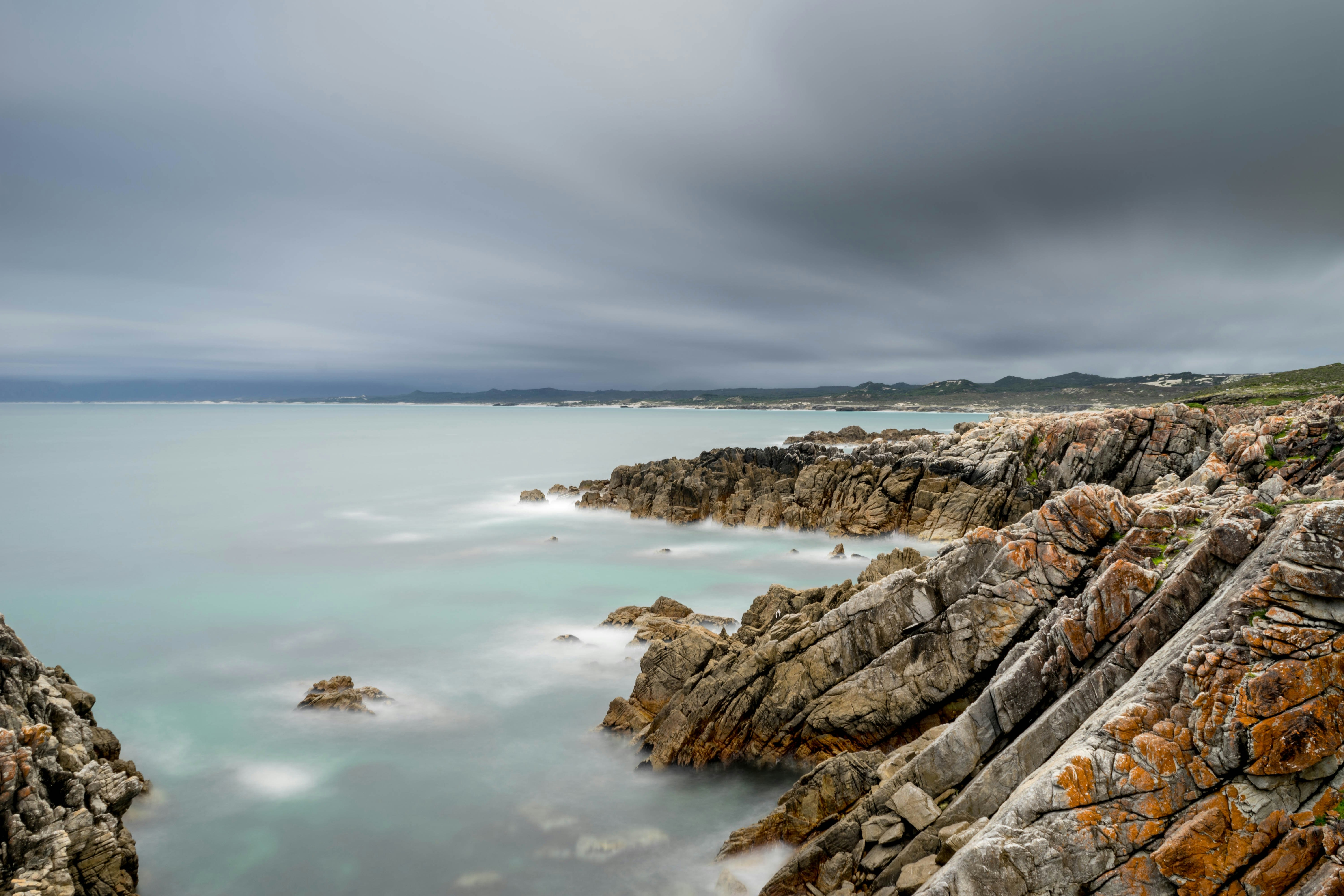 brown and gray rock formation on sea under gray sky