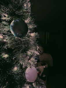 Warm white string lights gently wrapped around a cozy Christmas tree branch, glowing softly in a dim room.