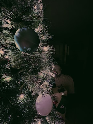 Warm white string lights gently wrapped around a cozy Christmas tree branch, glowing softly in a dim room.