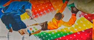A colorful mural depicts a soccer scene with a player in a blue uniform and a goalkeeper in an orange jersey. The background is filled with vibrant geometric patterns and swirling colors.